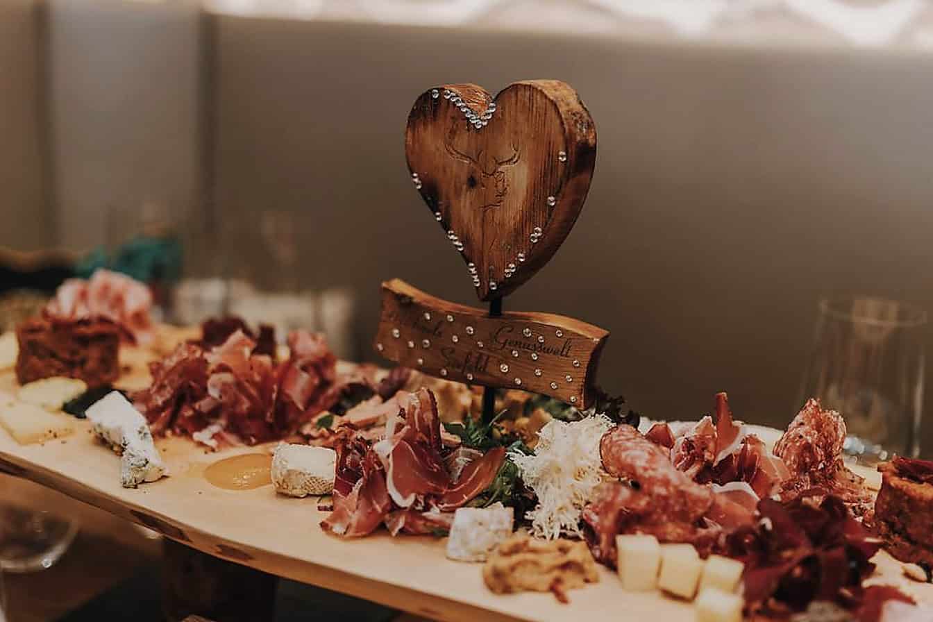 Liebevoll angerichtete Tiroler Feinkost mit Schinken, Käse und regionalen Spezialitäten in warmer Stubenatmosphäre