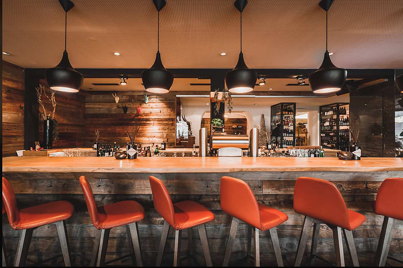 Stilvolle Restaurantbar mit rustikalem Holzdesign, roter Bestuhlung und warmem Lichtambiente